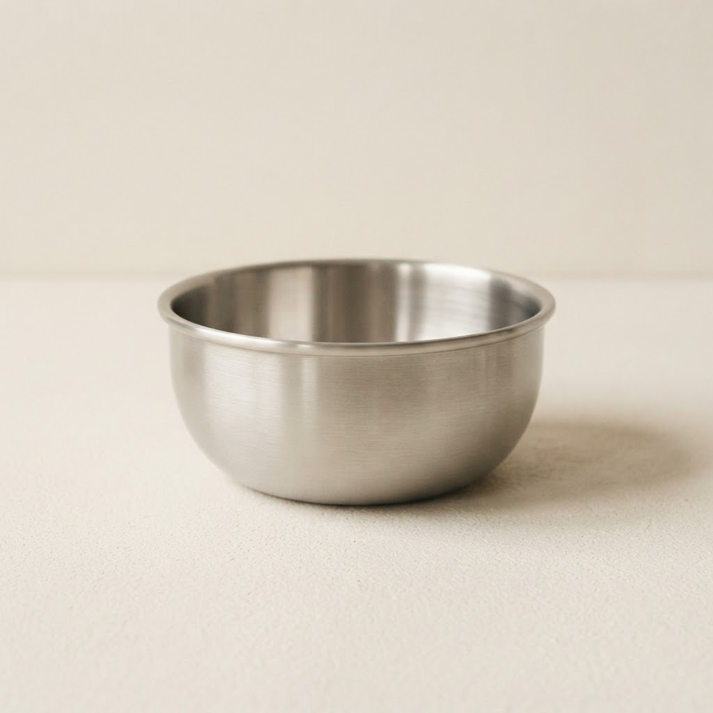 Medium brushed stainless steel cereal bowl on a warm off-white background