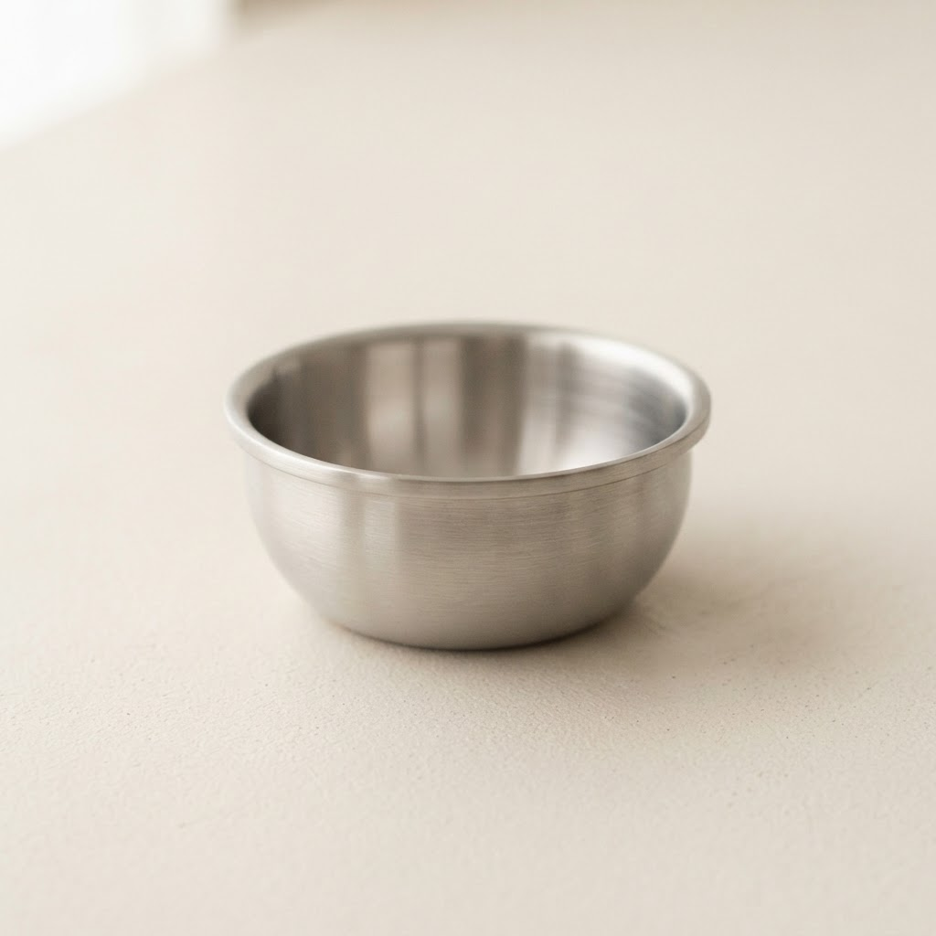 Small brushed stainless steel prep bowl on a warm off-white background